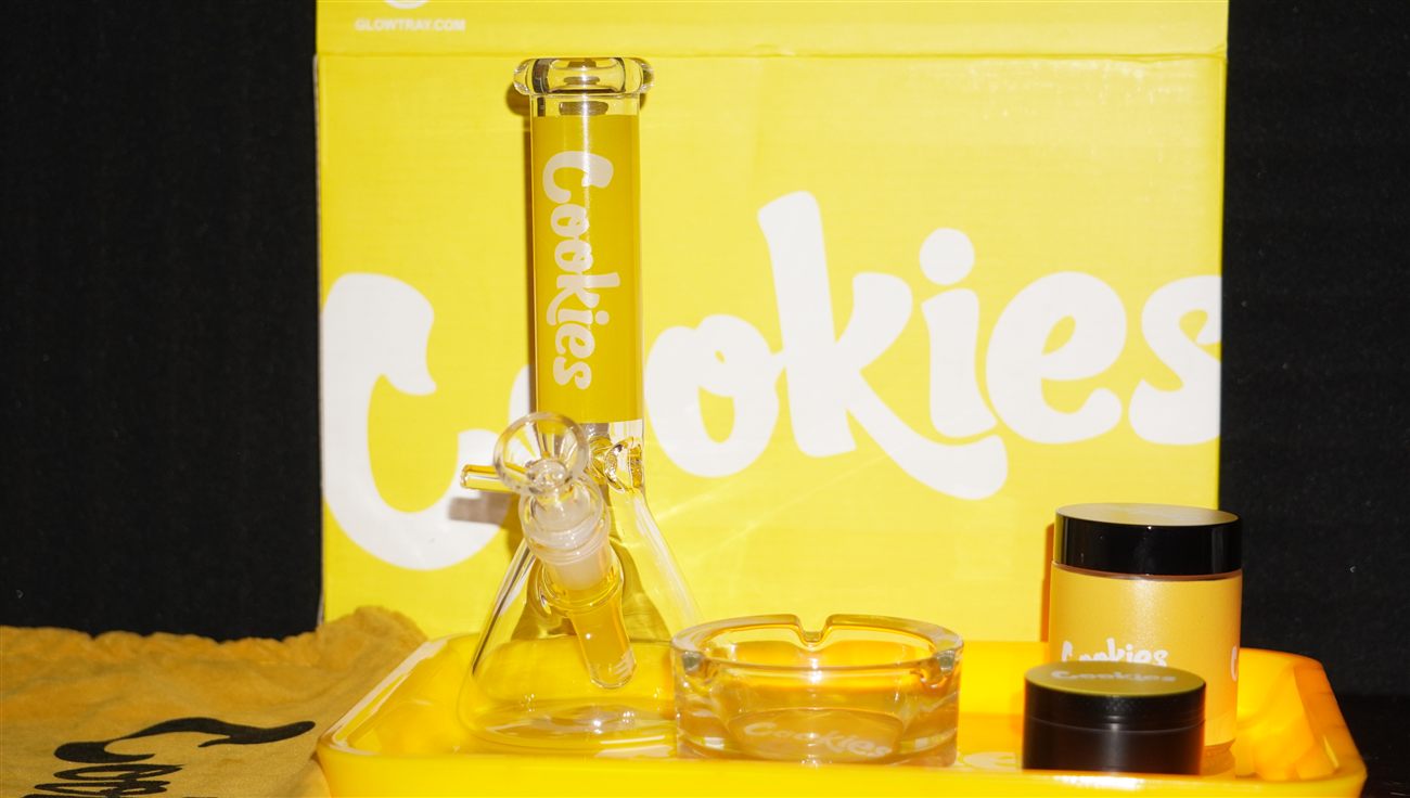 A bright yellow Cookies-branded rolling tray with a bong and grinder