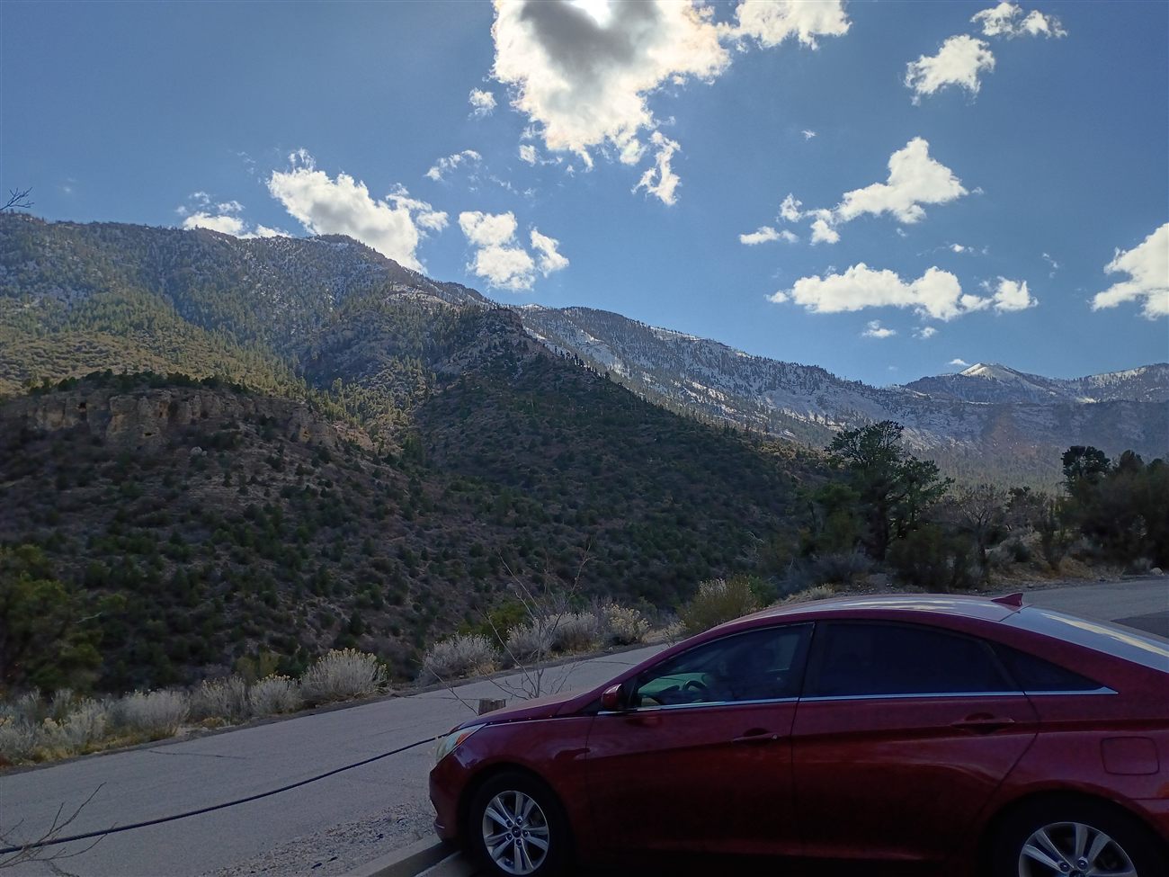 A snowy mountain ridge with a red car parked on the roadside
