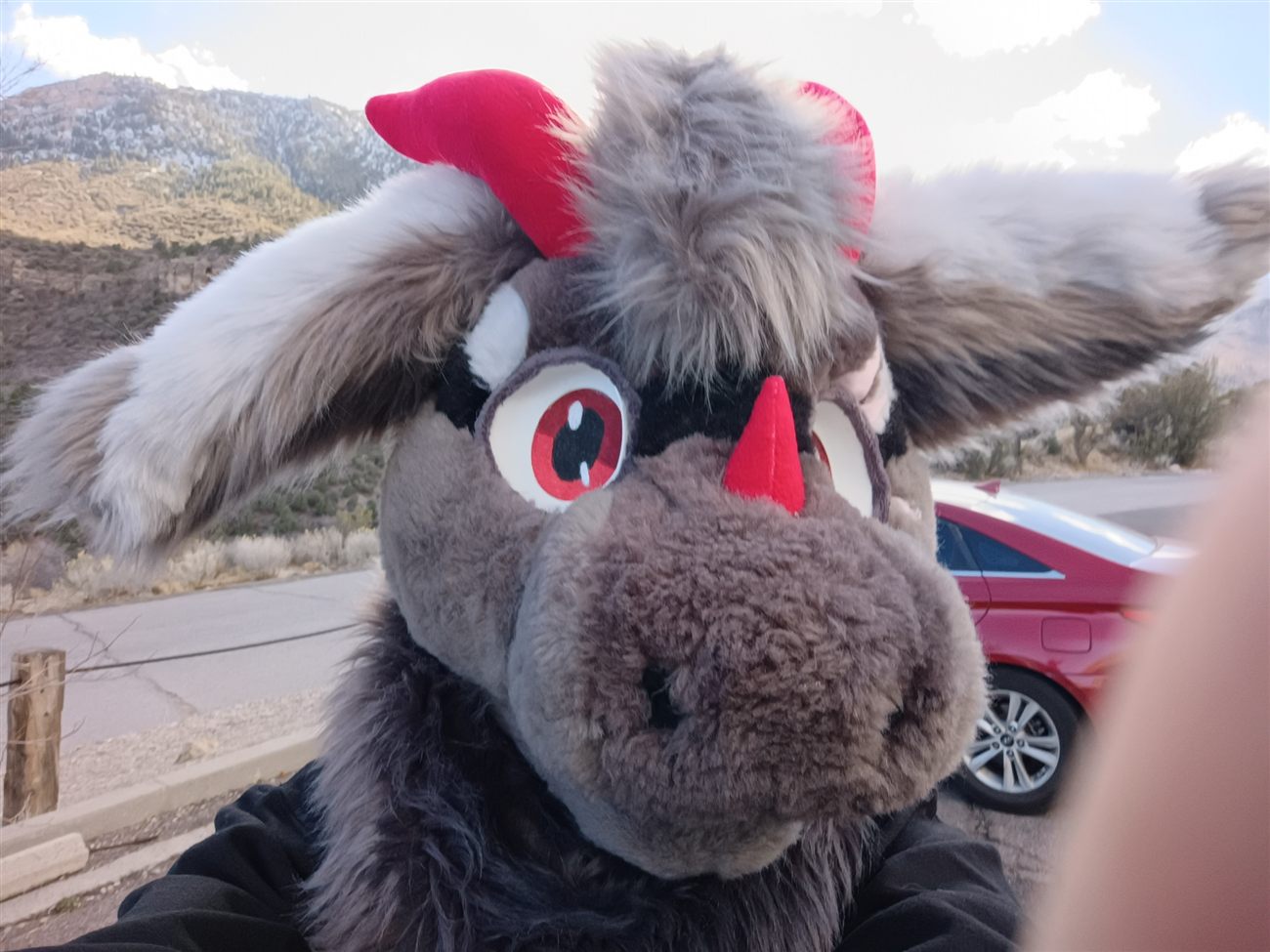A grey and white premade fursuit head with red horns and ears