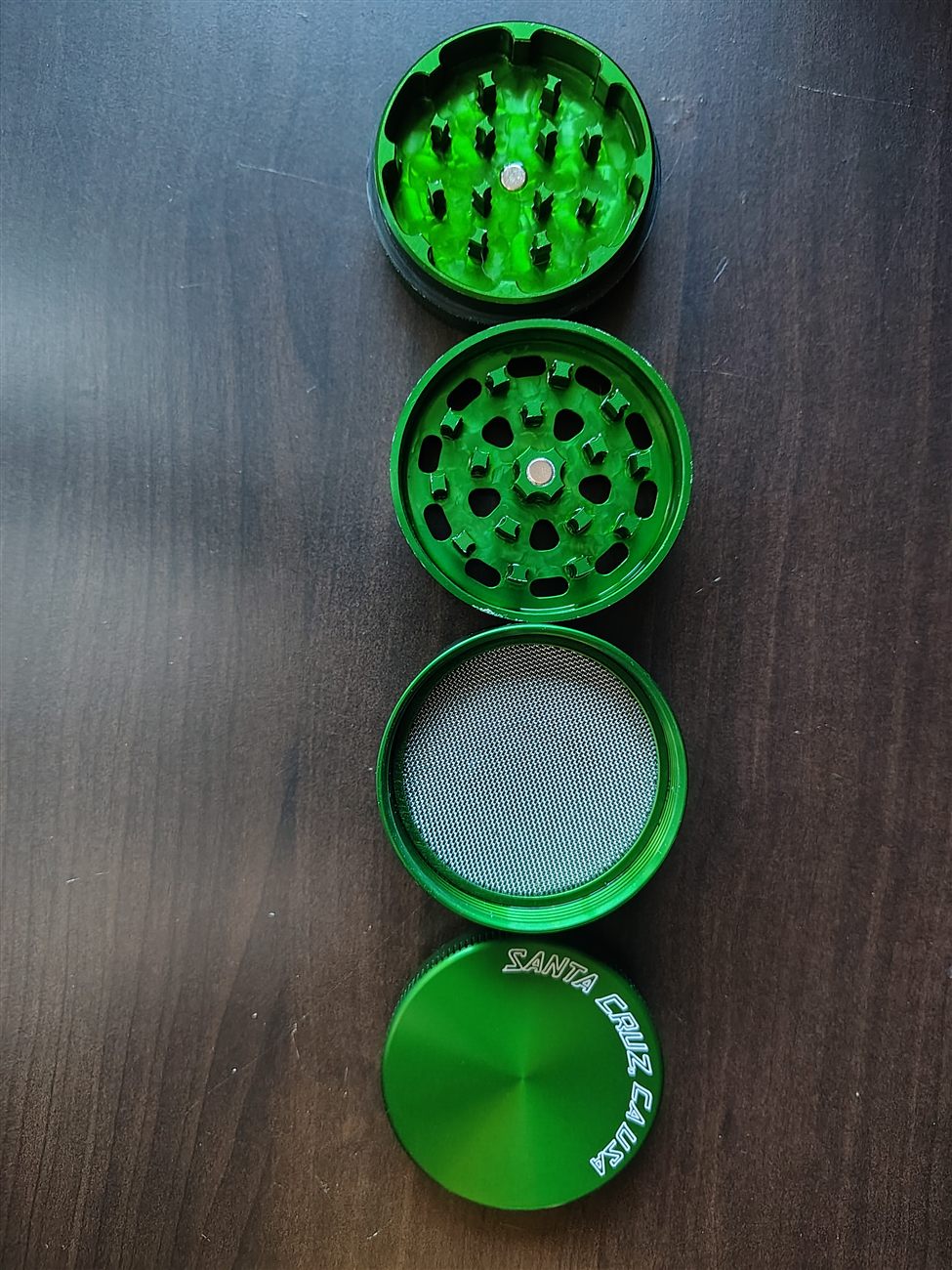 A green Santa Cruz Shredder grinder disassembled into its four pieces