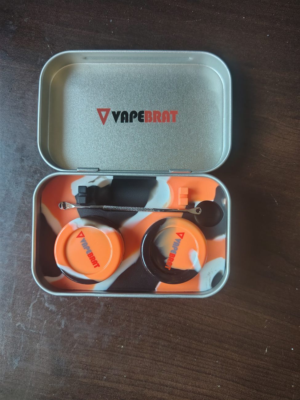 An open VapeBrat tin with silicone containers and a dab tool